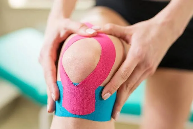 Kne med rosa og blå kinesiotape rundt kneskåla